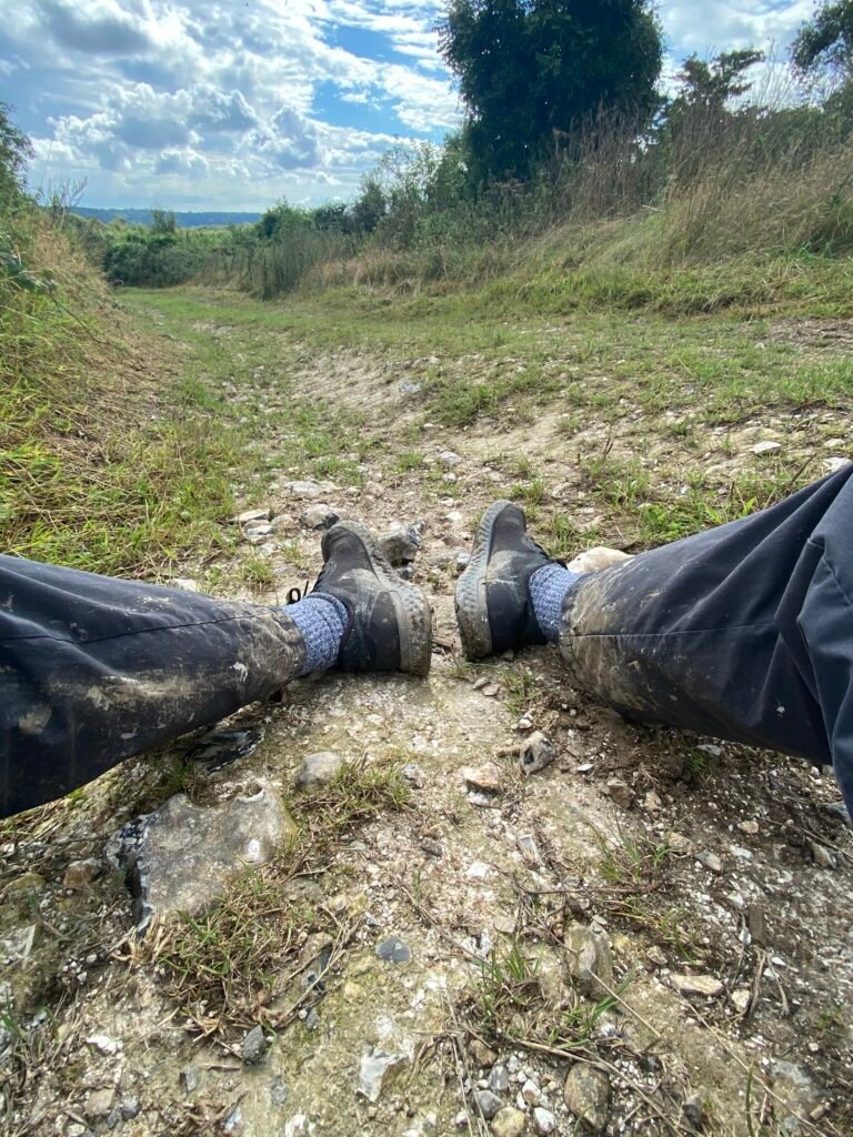 POV view of muddy trainers and trousers while sitting on the ground