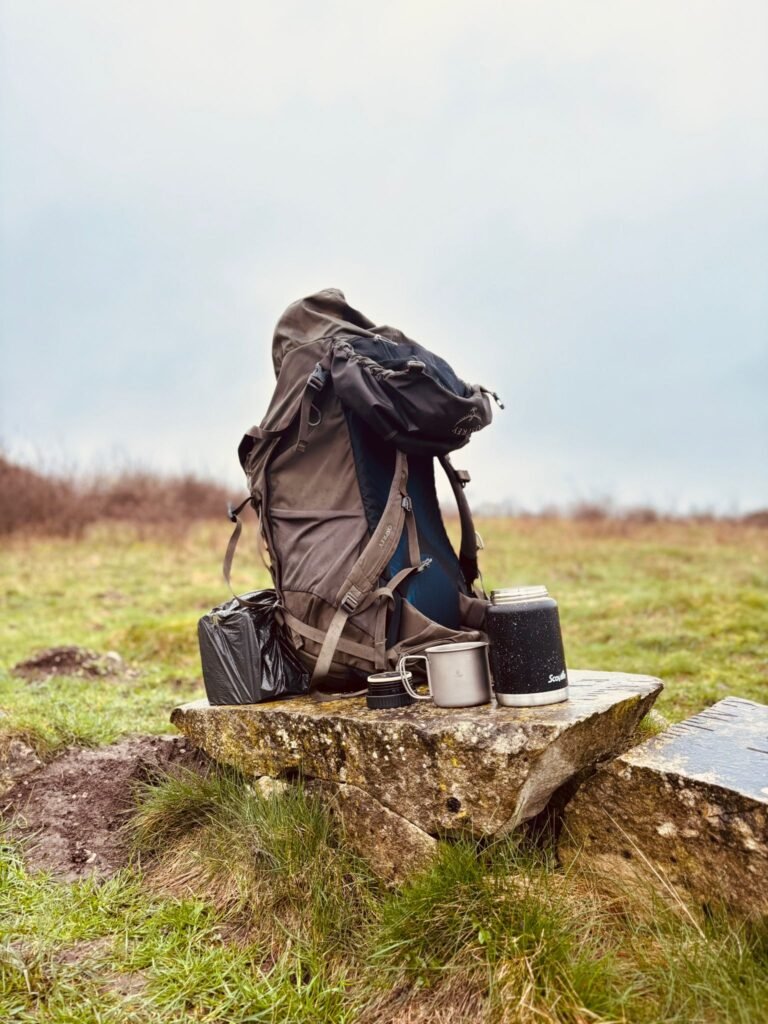 Backpack with cup and flask on a milestone during a wild camping rest break