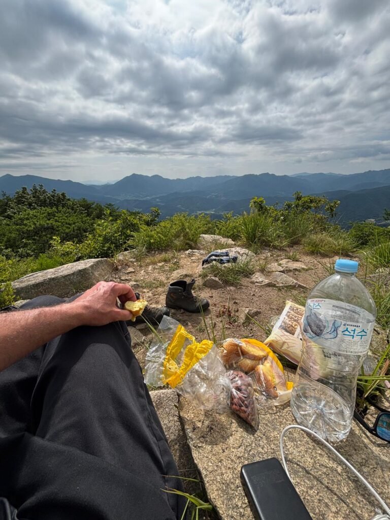 POV photo from the top of Misungsan with my snacks and water in front, looking out toward the larger mountains in the distance.