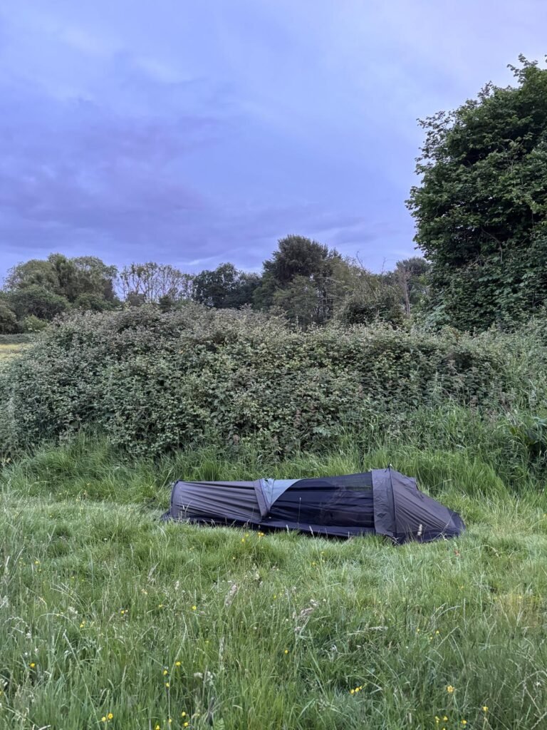 The Nortent Skjul, set up in grass, with the top unzipped and the bug net exposed