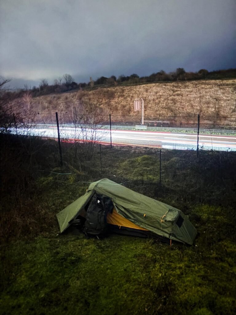 The OEX Phoxx 1v2 set up on a grass bank, with the long exposure lights of a motorway behind.