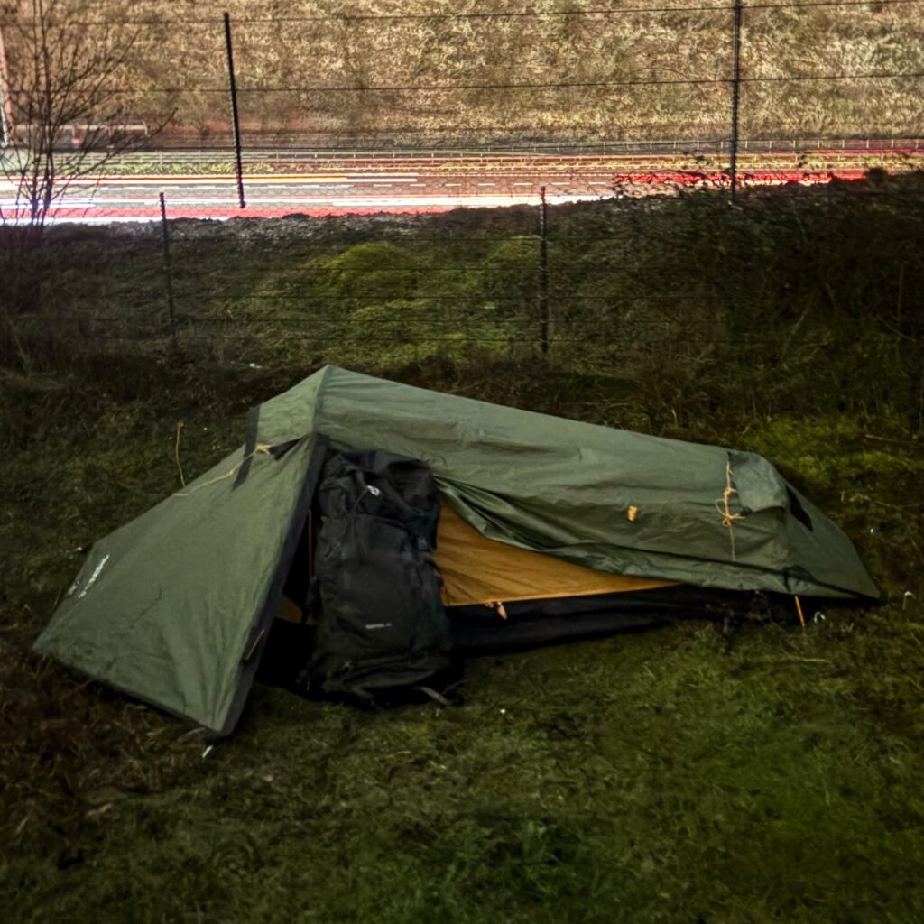 OEX Phoxx 1 V2 tent pitched on a grassy cliff top at dawn at St Aldhelm’s Head, Dorset, under a purple sky with a countryside building in the background