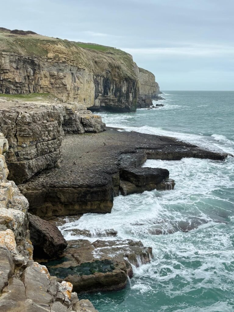 Flat rock platform of Dancing Ledge with amphitheatre-like cliffs dropping to the sea on the Dorset coast