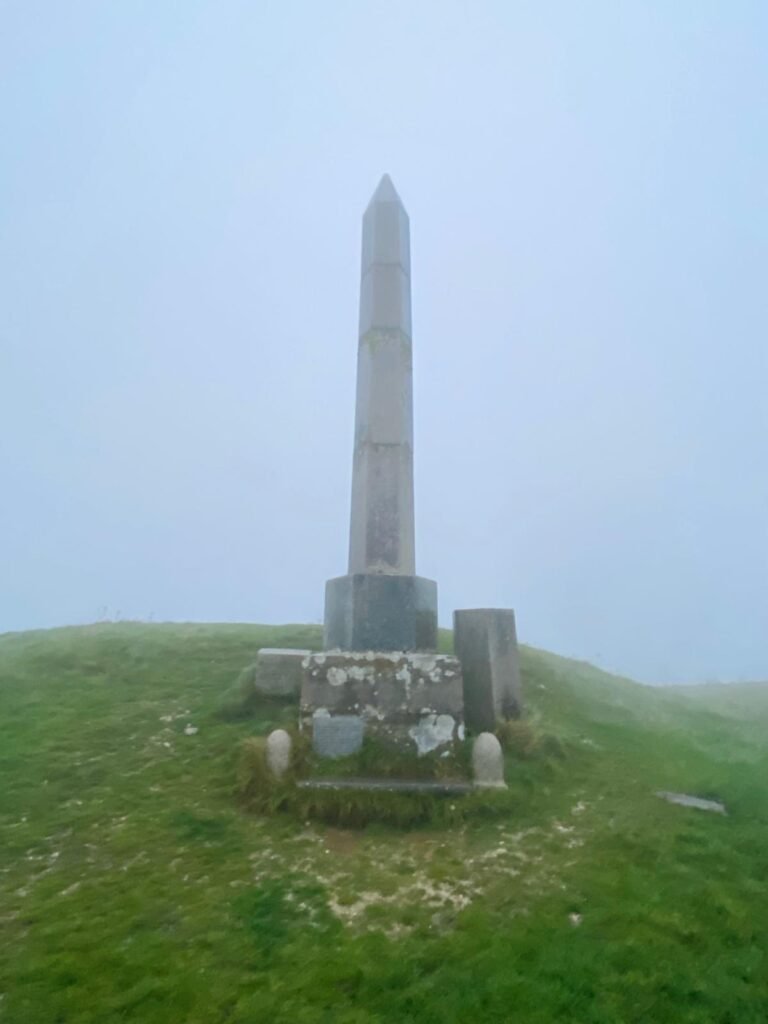 Obelisk on Ballard Down standing on a prehistoric barrow in misty coastal conditions near Swanage, Dorset