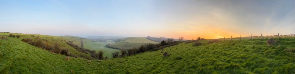 Panoramic view from Melbury Down at sunrise over Dorset landscape