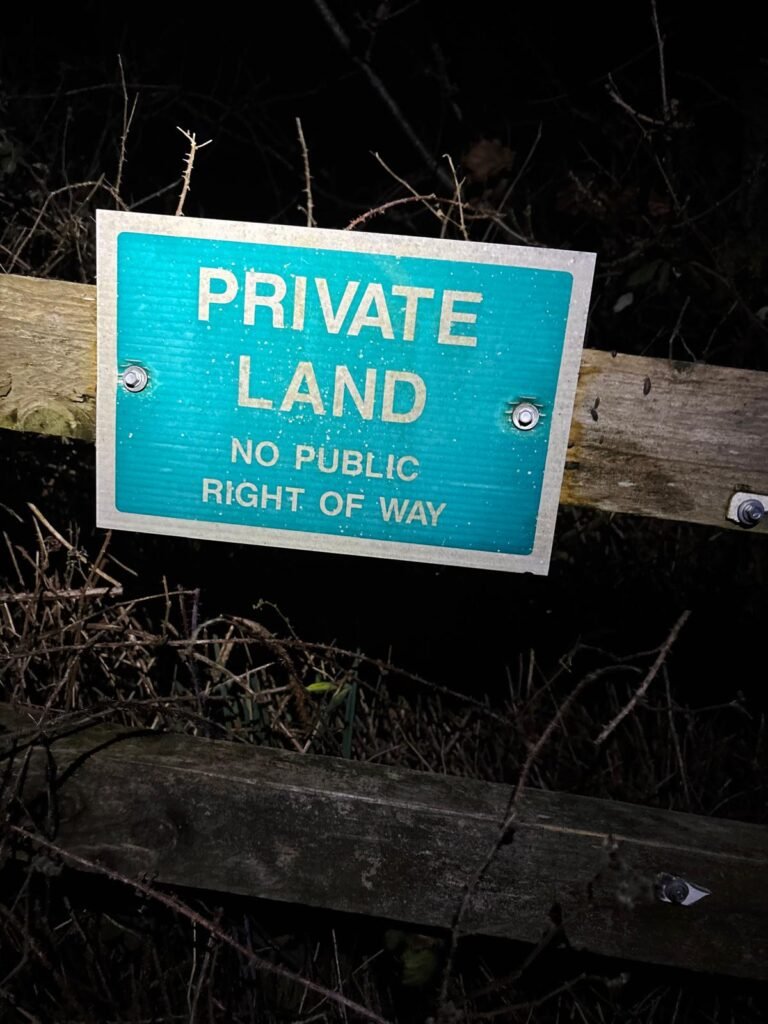 Private land sign attached to a wooden fence with no public right of way warning