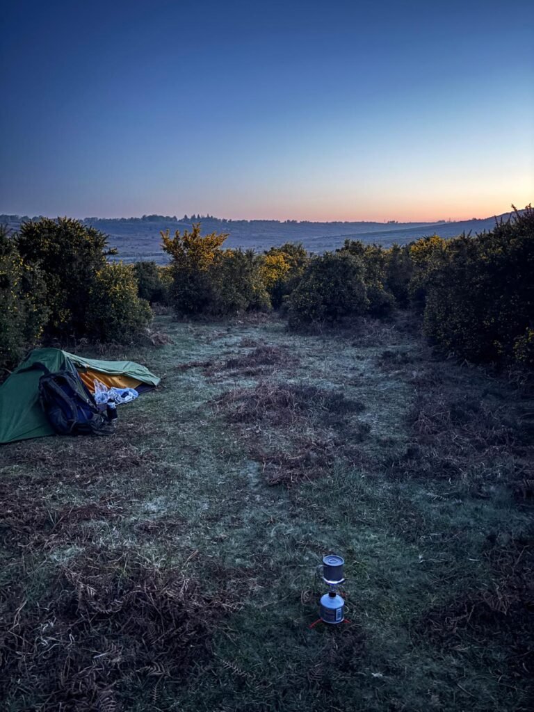 Morning coffee boiling beside a tent at dawn in the New Forest