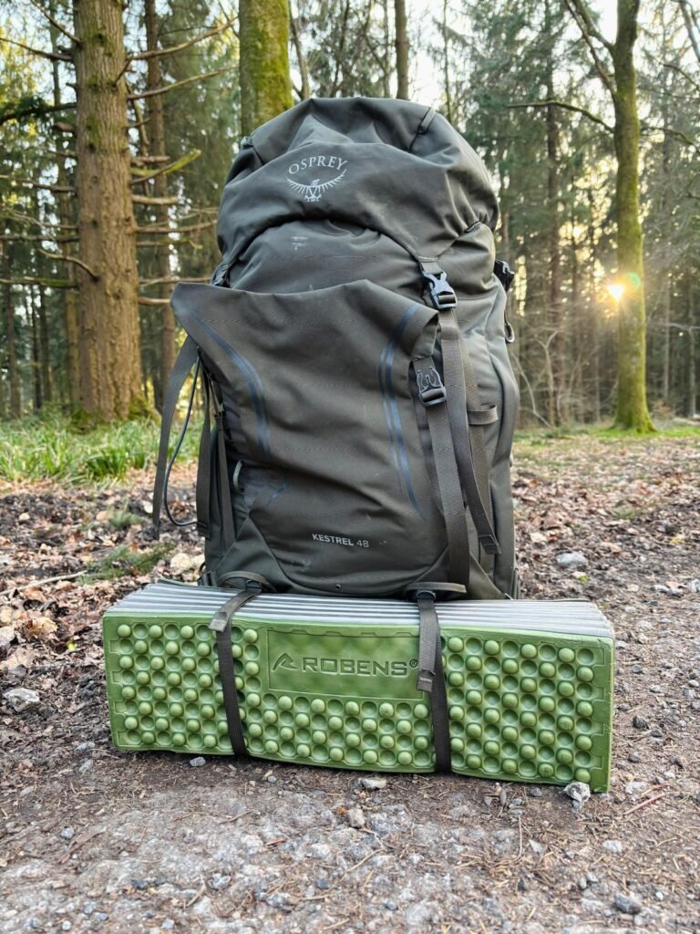 Fully packed Osprey backpack with sleeping mat attached during forest wild camp