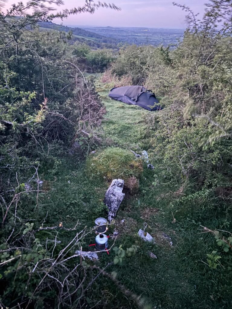 Morning coffee beside a Nortent Skjul bivvi sheltered from the wind by bushes
