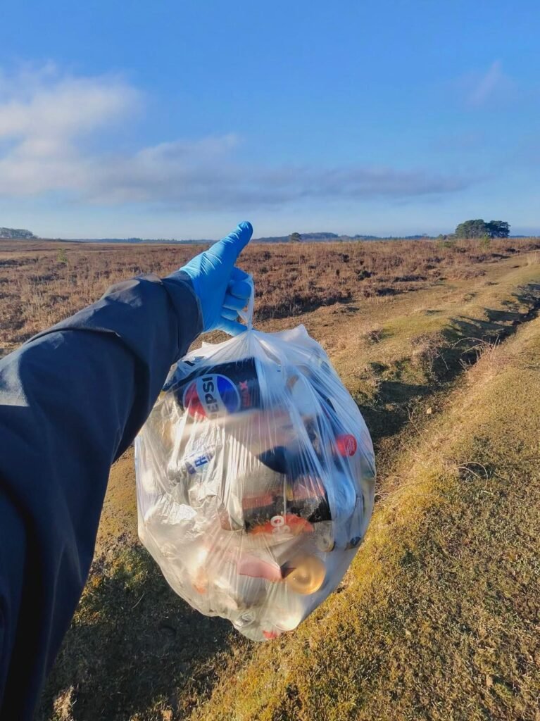 Full bag of litter collected in the New Forest held up against a heathland landscape.