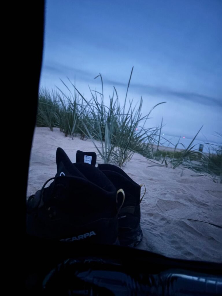 View from inside a Nortent Skjul bivvi shelter overlooking a misty beach and sea during a wild camping trip in Dorset.