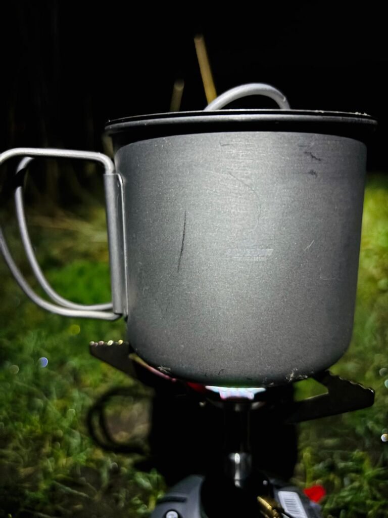 Scratched SilverAnt titanium cup on a gas stove while camping