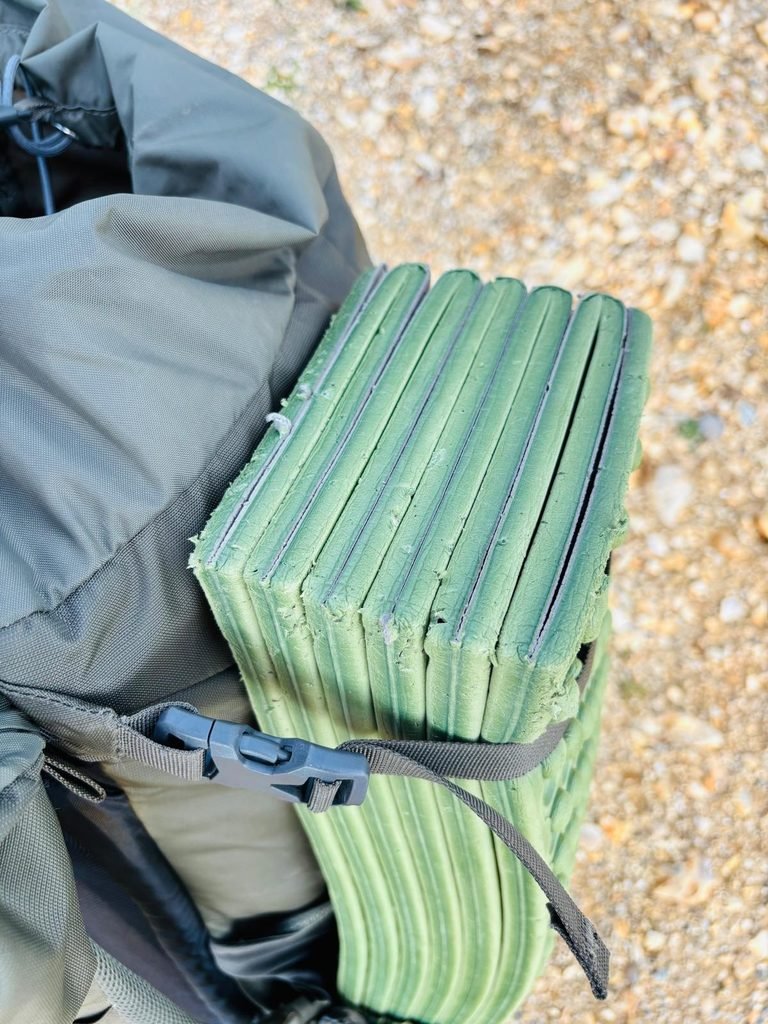 Scratched sleeping mat strapped to my bag on a camp.