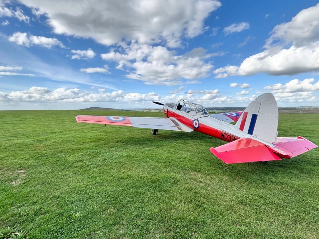 White and red propeller aircraft beside the grass runway at Compton Abbas Airfield